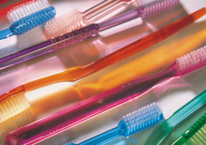 Mehrere bunte Zahnbürsten mit transparenten Griffen liegen nebeneinander – Symbolbild für Zahnpflege und Mundhygiene.